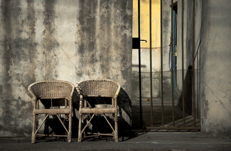 Two rattan chairs in a back alleyの写真素材