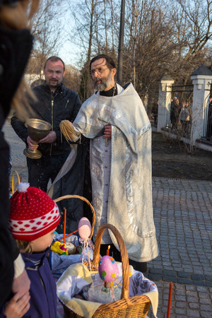 MOSCOW - APRIL 11, 2015: Orthodox priest sprinkles Easter eggs and cakes holy waterのeditorial素材