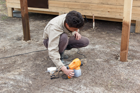 man preparing spray gun for painting wooden structureの写真素材