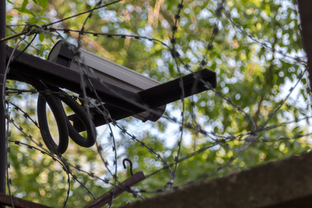 surveillance camera on a concrete fence with barbed wire