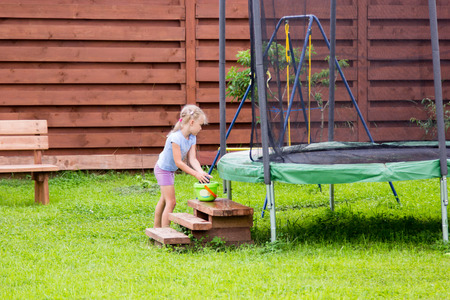 little girl washes her trampoline in the backyardの写真素材