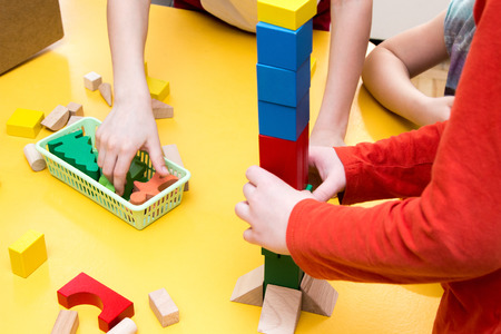 Children build a tower of wooden blocks on the table