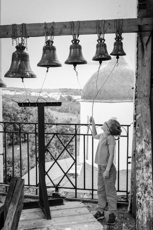 Girl rings bells in the bell tower of the old Russian Orthodox Churchの写真素材