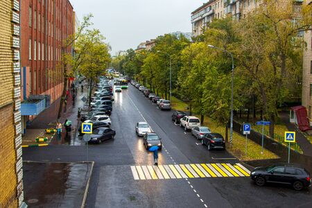 calm city street with cars and pedestrians in the rainの写真素材