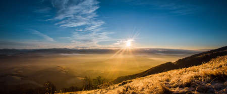 Sunrise in fog mountains in autumn winterの写真素材