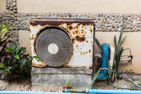 Old rusty air conditioner is located behind the building.の写真素材