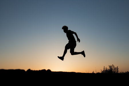 Generative AI Image of Silhouette of Man Jumping in Field at Sunsetの素材