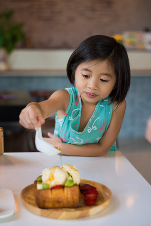 The hands of a girl who is pouring honey into a toast. Honey Toast. Bread buttered toast.の写真素材