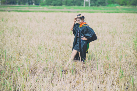Woman smiling at her graduation on dry grasslandsの写真素材