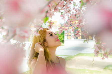 Spring beauty girl with long red blowing hair outdoors. Blooming trees. Romantic young woman portrait. Natureの写真素材