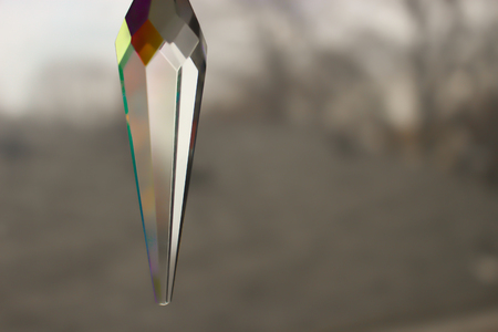 A beautiful hanging suncatcher crystal with red, orange, and blue splashes of color.の写真素材