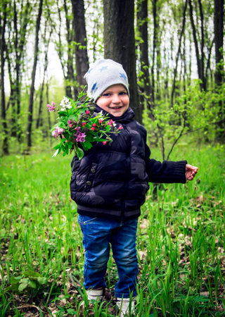 Boy with a bouquet of flowers in the forest