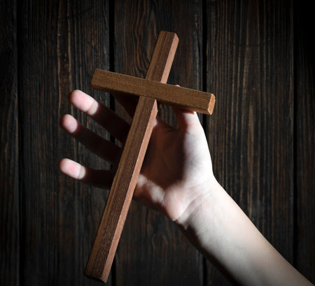 wooden cross in a child's hand, on wooden backgroundの写真素材