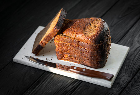 black bread on a wooden board on a black background