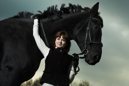 Beautiful young woman with a black horseの写真素材