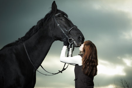 Beautiful young woman with a black horseの写真素材