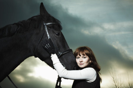 Beautiful young woman with a black horseの写真素材