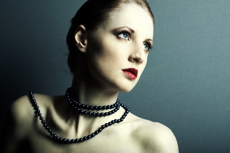 The beautiful young girl with a dark blue beads on a neckの写真素材