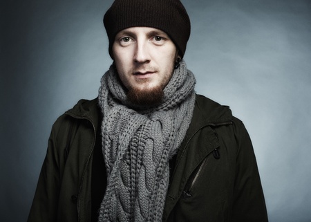 Artistic dark portrait of the young beautiful man in a cap and a dark jacketの写真素材
