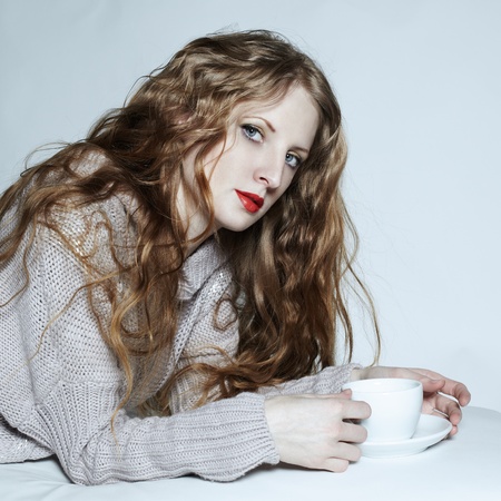 Portrait woman with a cup of coffee lying on a sofaの写真素材