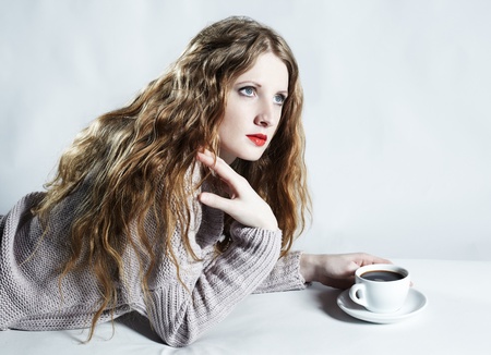 Portrait woman with a cup of coffee lying on a sofaの写真素材