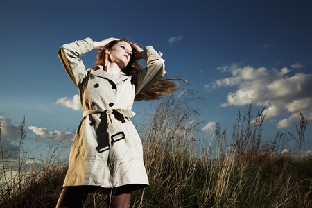 Fashion portrait of elegant woman in a raincoat on the natureの写真素材