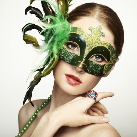 The beautiful young woman in a green mysterious venetian mask の写真素材