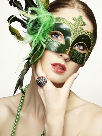 The beautiful young woman in a green mysterious venetian mask の写真素材