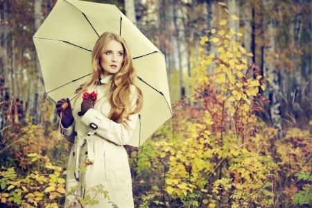 Fashion portrait of a beautiful young woman in autumn forest. Girl with umbrellaの写真素材