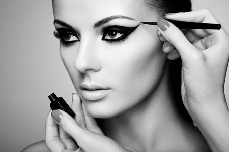 Makeup artist applies eye shadow. Beautiful woman face. Perfect makeup. Black and white photoの写真素材