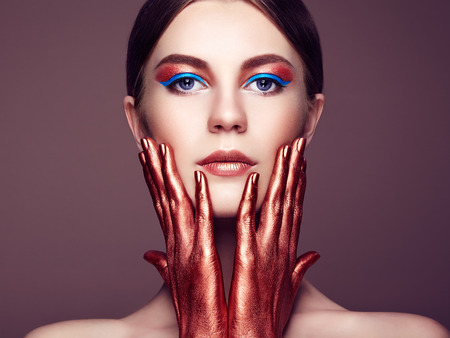 Portrait of beautiful young woman with art make-up. Bronze hand. Beauty fashionの写真素材
