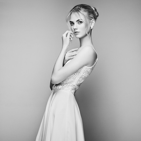 Fashion portrait of beautiful young woman with blond hair. Girl in white dress on white backgroundの写真素材