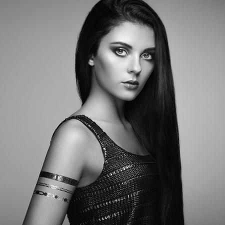 Fashion portrait of elegant woman with magnificent hair. Brunette girl. Perfect make-up. Girl in elegant dress. Flash tattoo goldの写真素材