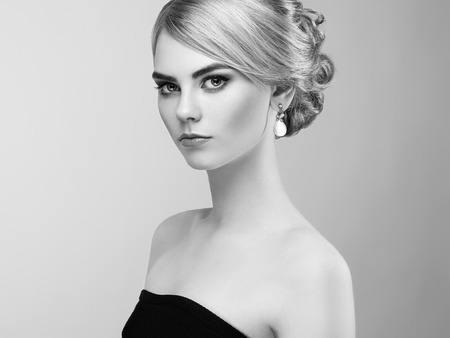 Portrait of beautiful sensual woman with elegant hairstyle.  Perfect makeup. Blonde girl. Fashion photo. Jewelry and dress. Black and whiteの写真素材