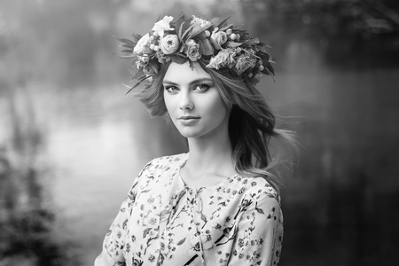 Beautiful blonde woman with flower wreath on her head. Beauty girl with flowers hairstyle. Girl in a summer forest. Fashion photo. Black and Whiteの写真素材