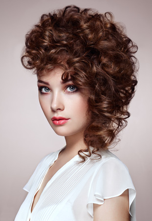 Brunette woman with curly and shiny hair. Beautiful model with wavy hairstyle. Fashion photoの写真素材