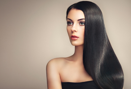 Beautiful woman with long smooth hair. Girl with perfect makeup and hairstyle. Model brunette with perfect healthy dark hairの写真素材