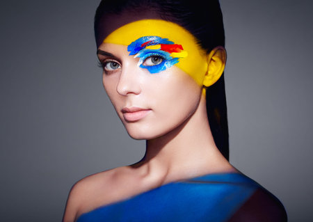 Fashion model woman with colored face painted. Beauty fashion art portrait of beautiful woman with...