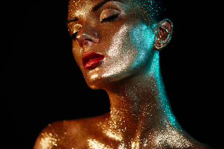 Portrait of Beautiful Woman with Sparkles on her Face. Girl with Art Make-Up in Color Light. Fashion Model with Colorful Makeup