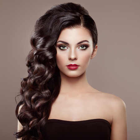 Brunette Woman with Curly Hairstyle. Beautiful Girl with long Wavy Hair. Perfect Makeup. Fashion photoの写真素材