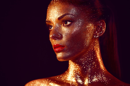 Portrait of Beautiful Woman with Sparkles on her Face. Girl with Art Make-Up in Color Light. Fashion Model with Colorful Makeupの写真素材
