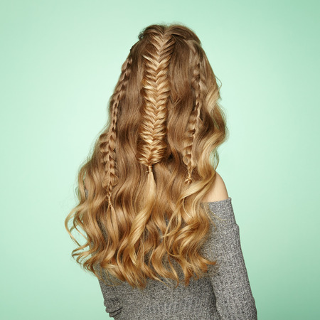 Blonde Girl with Long and Shiny Curly Hair. Beautiful Model Woman with Curly Hairstyle. Care and Beauty Hair Products. Lady with braided hairの写真素材