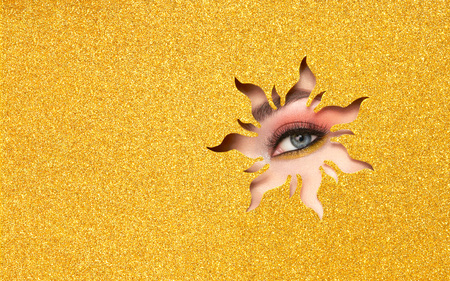 The Eyes of the Young Beautiful Woman with Bright Pink Shadows and Expressive Eyebrows, Looks in the Solar Shaped Pattern out of Yellow Paper. Yellow Sun. Summer Patterns. Advertising Bannerの写真素材