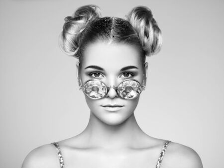 Portrait of beautiful young woman in sunglasses. Beauty Fashion. Black and white photo. Hair Curled into a Bunの写真素材