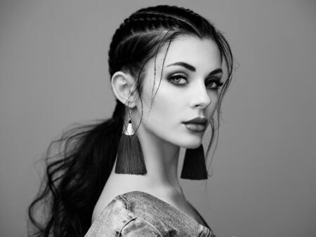 Brunette girl with perfect makeup. Beautiful model woman with curly hairstyle. Care and beauty hair products. Lady with braided hair. Model with jewelry. Black and white photoの写真素材