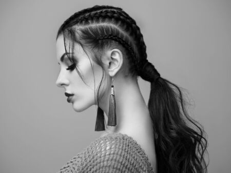 Brunette girl with perfect makeup. Beautiful model woman with curly hairstyle. Care and beauty hair products. Lady with braided hair. Model with jewelry. Black and white photoの写真素材
