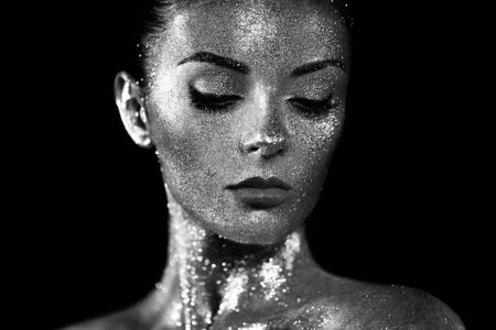 Fashion model woman in bright sparkles and lights posing in studio. Portrait of beautiful sexy woman. Art design glitter glowing make up. Black and white photographyの写真素材