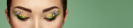 Eye makeup girl with a flowers. Spring makeup. Beauty fashion. Eyelashes. Cosmetic Eyeshadow. Make-up detail. Creative woman holiday make-upの写真素材
