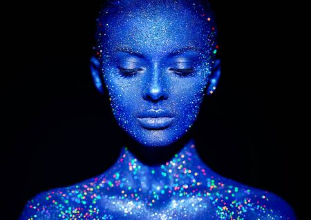 Fashion model woman in blue bright sparkles and neon lights posing in studio.  Portrait of beautiful sexy woman. Art design colorful glitter glowing make upの写真素材