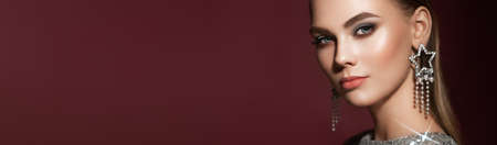 Portrait beautiful woman with jewelry. Brunette girl with long smooth hair. Beauty fashion. Eyelashes. Cosmetic eyeshadow. Care and beauty hair products. Model in a silver dressの写真素材